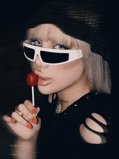 Chic portrait of a young woman in sunglasses enjoying a lollipop.