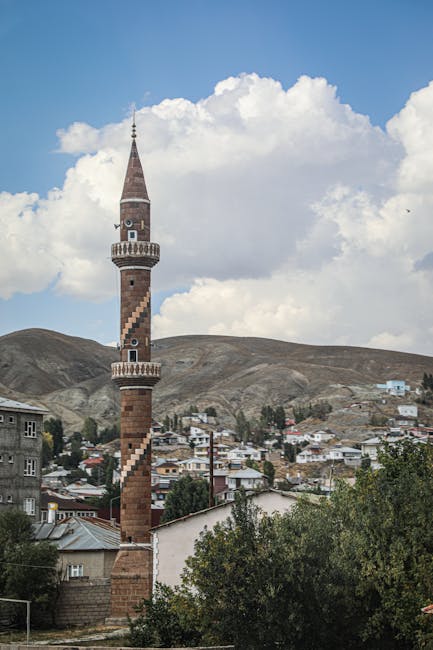 Dramatic view of a unique minaret in a Turkish mountain village under a cloudy sky.