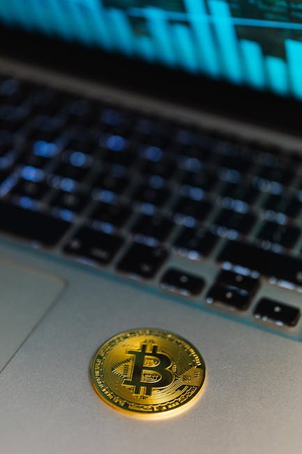 Close-up of a Bitcoin coin on a laptop, with a graph display in the background representing cryptocurrency technology.