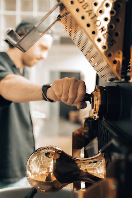 Close-up of a man operating a coffee roaster machine in a modern factory setting.
