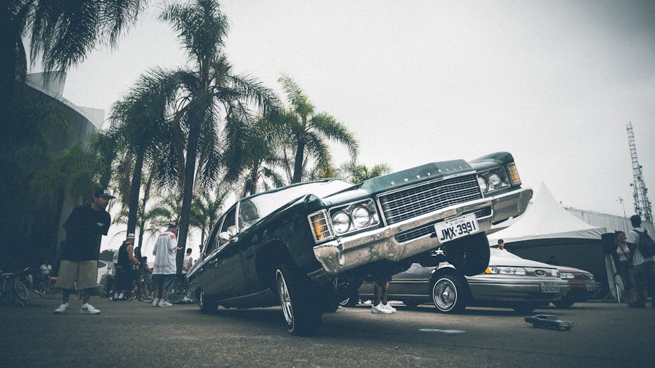 A vibrant lowrider car with palm trees and people at an outdoor car show.