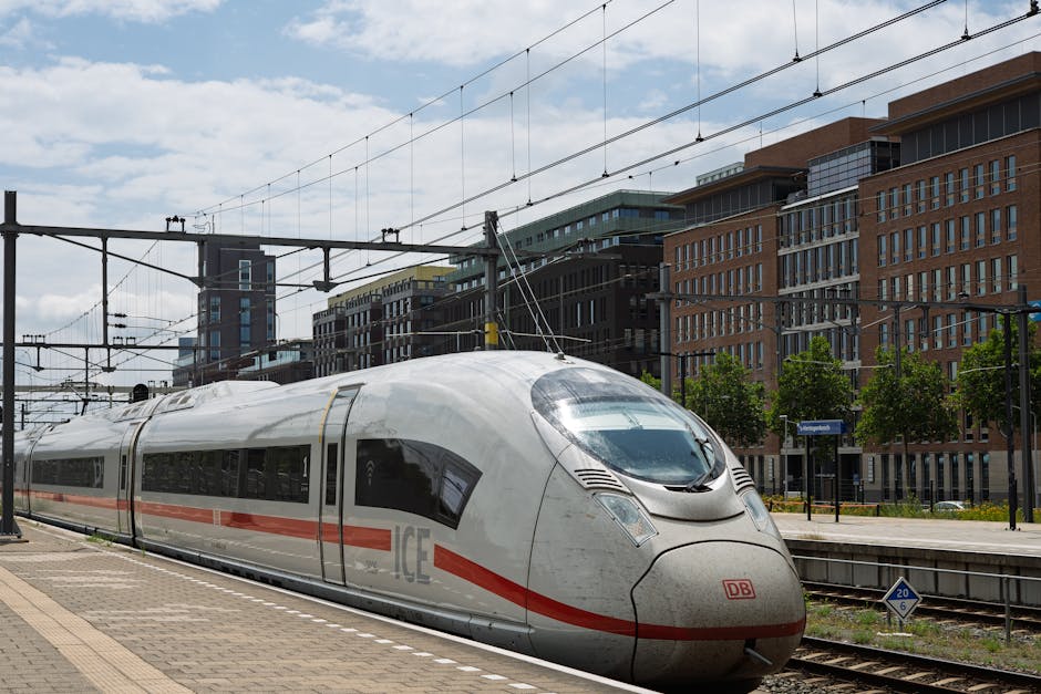 High-speed ICE train at a city station platform, urban architecture in background.