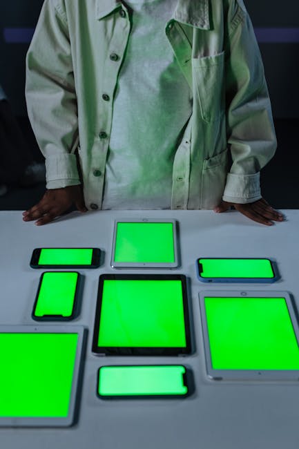 Nine digital devices on a table with green screens, ready for content editing.