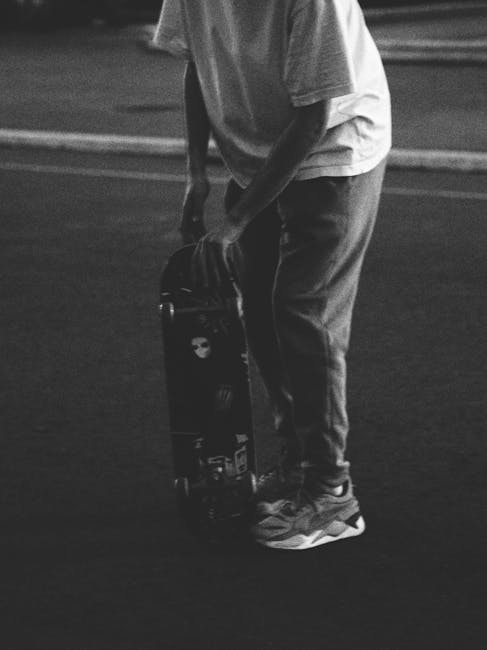 Black and white photo of a person with a skateboard in an urban setting, captured at night.