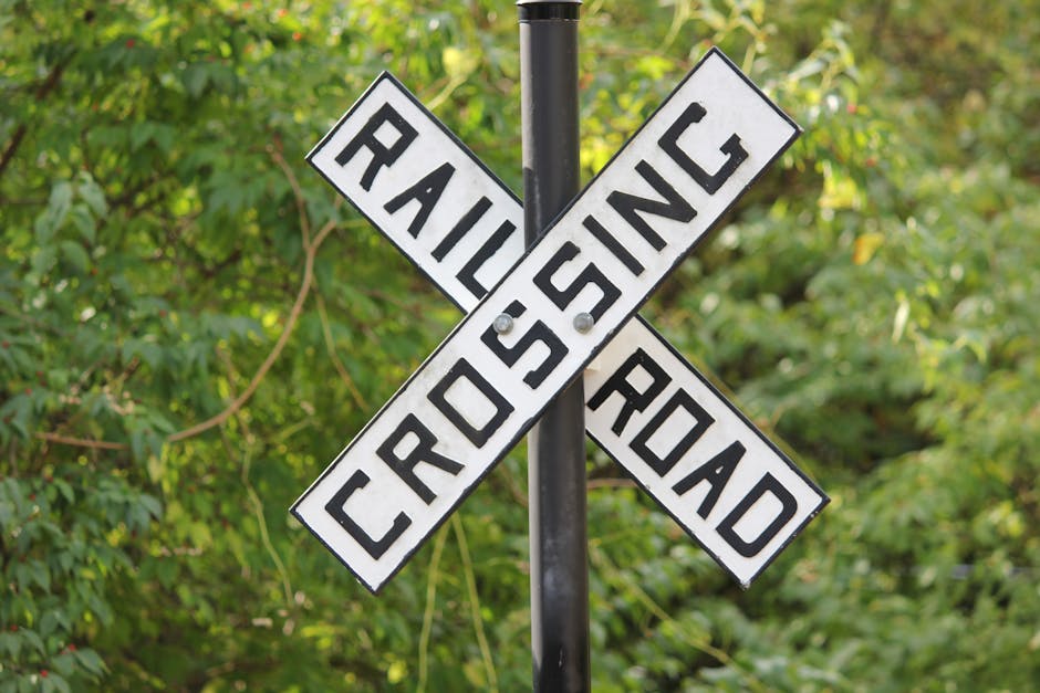 Detailed view of a railroad crossing sign with vibrant green foliage background.