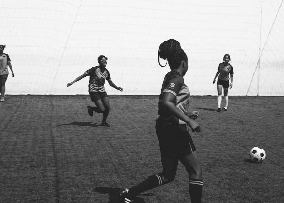 Female soccer players competing in an outdoor match on a sports field.