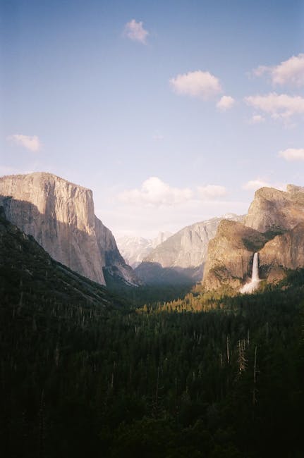 Experience the stunning beauty of Yosemite Valley's waterfall with towering cliffs and lush greenery.