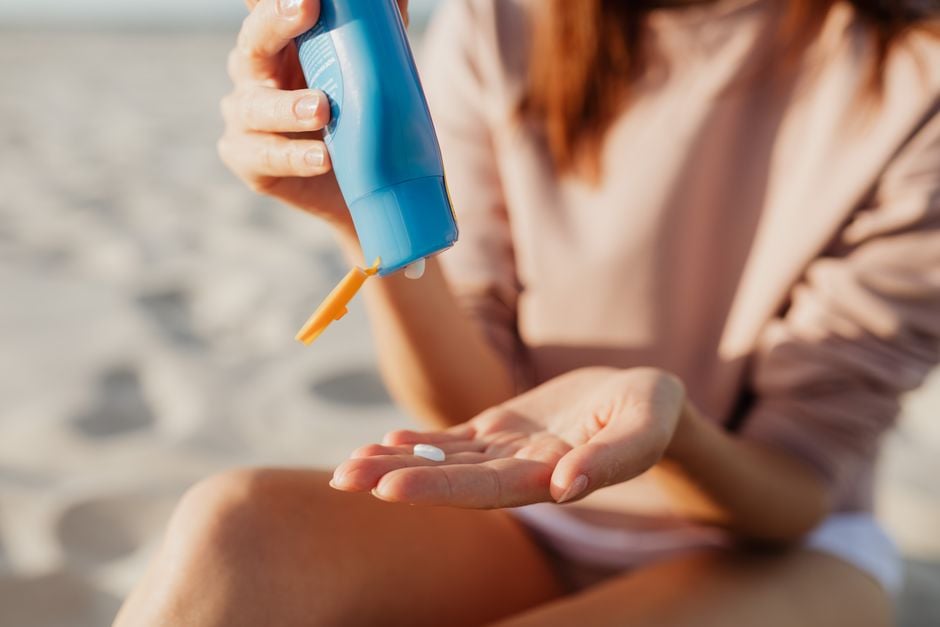 applying sunscreen on shoulder by the ocean beach SPF bottle