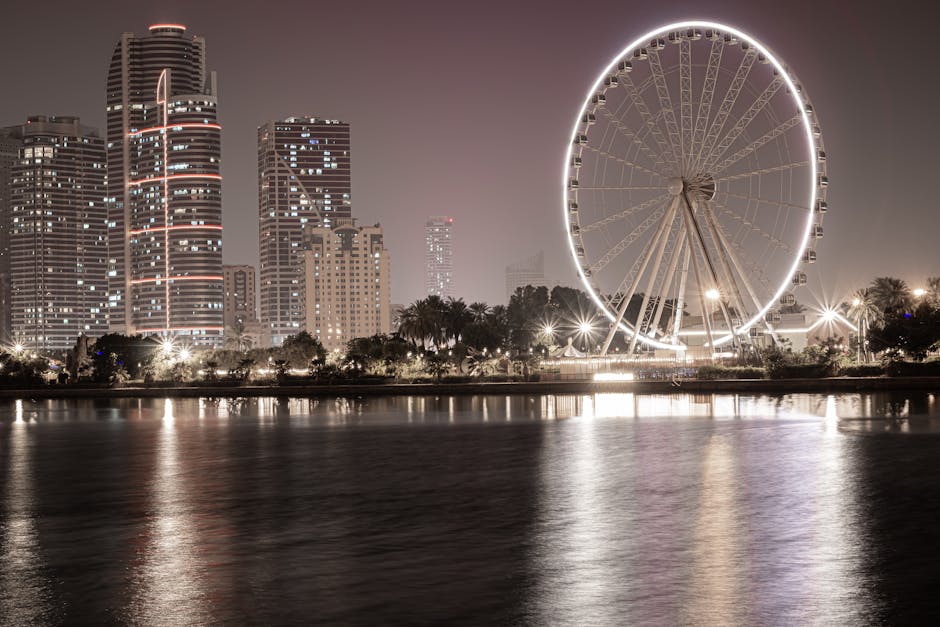 Discover the vibrant skyline and Ferris wheel along Sharjah's waterfront at dusk.