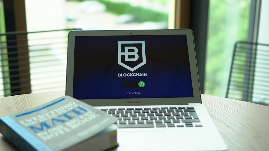 A laptop displays a blockchain screen next to a math textbook, symbolizing digital finance and education.