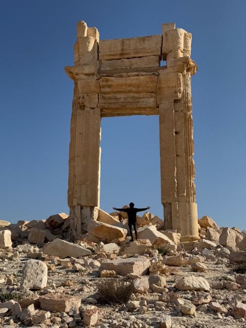 A person stands amidst the ancient ruins of Palmyra in Syria.