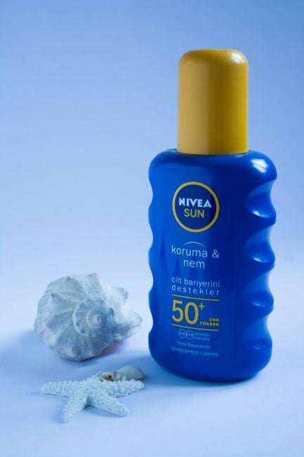 Nivea Sun SPF 50+ lotion with seashells on a blue backdrop, ideal for summer skincare.