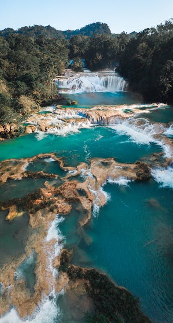 A breathtaking aerial view of stunning turquoise waterfalls amidst lush greenery.