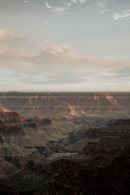 Drone view of rocky formations with steep slopes located in canyon against cloudy sky in nature in dry terrain outside