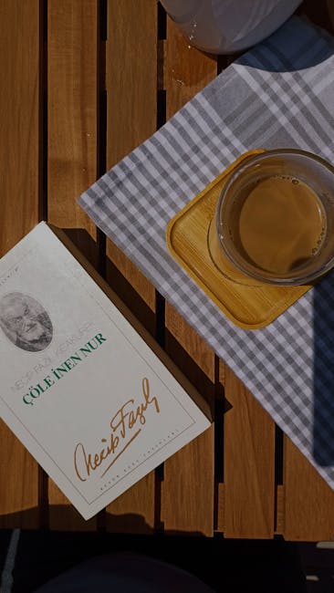 Overhead view of a book and coffee on a wooden picnic table in İzmit, Türkiye.