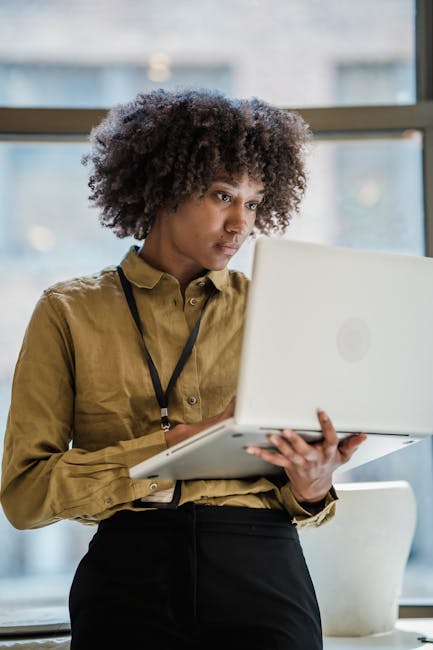 Focused businesswoman with curly hair works on a laptop in a modern office.