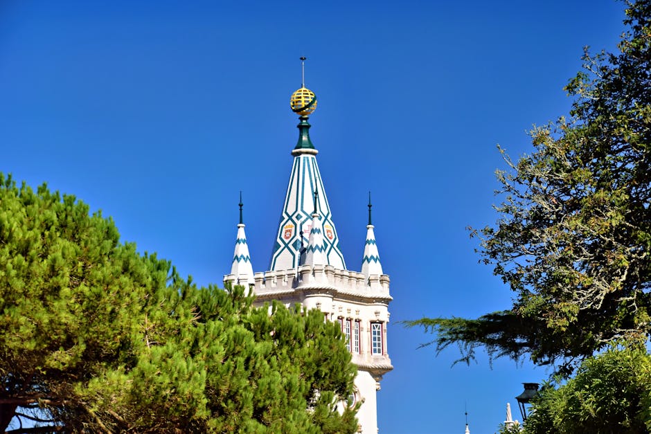 Stunning view of Sintra's iconic tower with a vibrant clear blue sky and lush greenery.