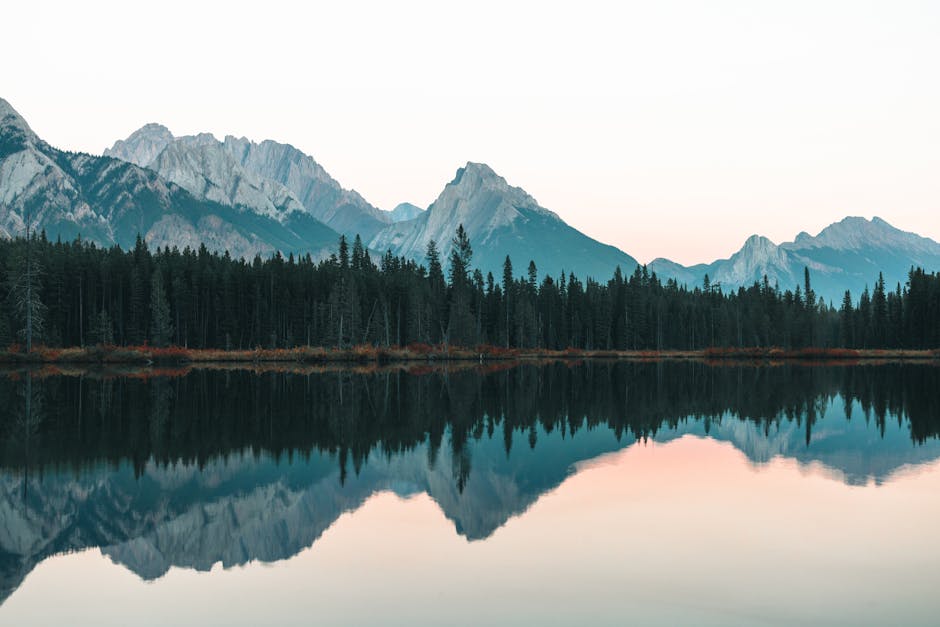 Breathtaking view of mountains reflecting in a calm lake at dawn in Kananaskis, Alberta, Canada.