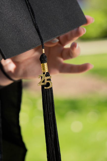Close-up of a graduation cap featuring a '25' tassel against a blurred outdoor background.