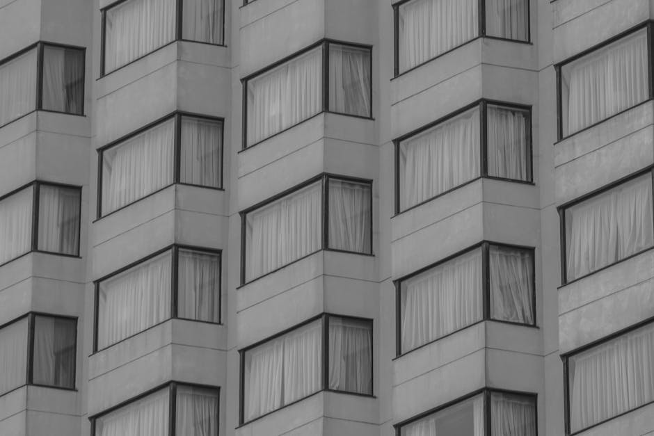 Black and white photo of modern apartment or hotel windows with curtains.