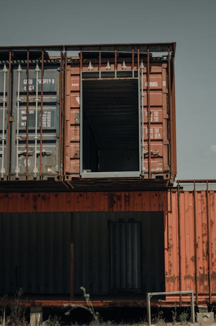 Vertical shot of rusty shipping containers stacked outdoors in Portugal.
