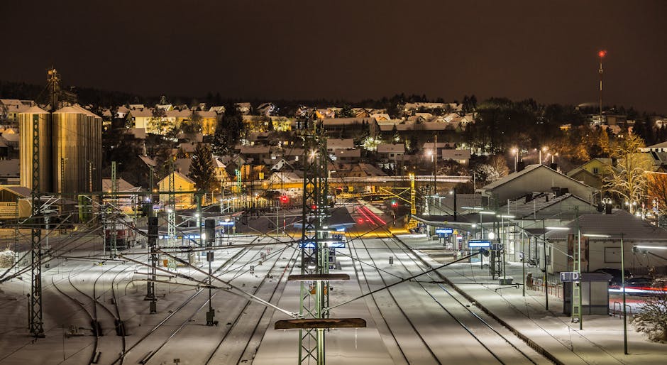 A snow-covered train station illuminated at night, showcasing urban architecture and transportation.
