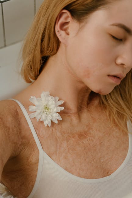 Portrait of a confident woman with burn scars and a white flower, promoting body positivity.