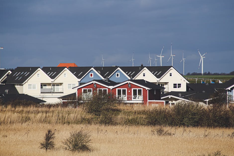 Charming rural houses with wind turbines in Dagebüll, Germany under cloudy skies.
