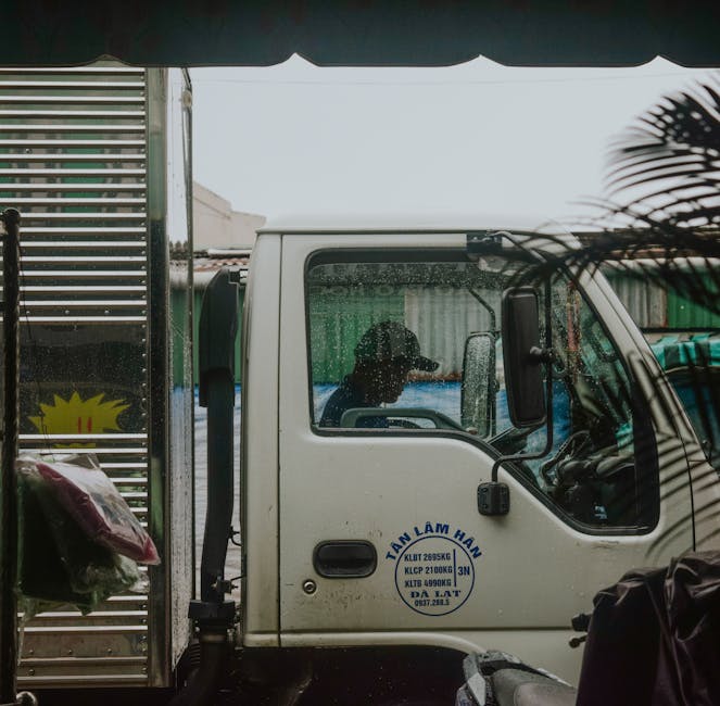 Side profile view of a truck driver inside cab during rain. Urban delivery concept.