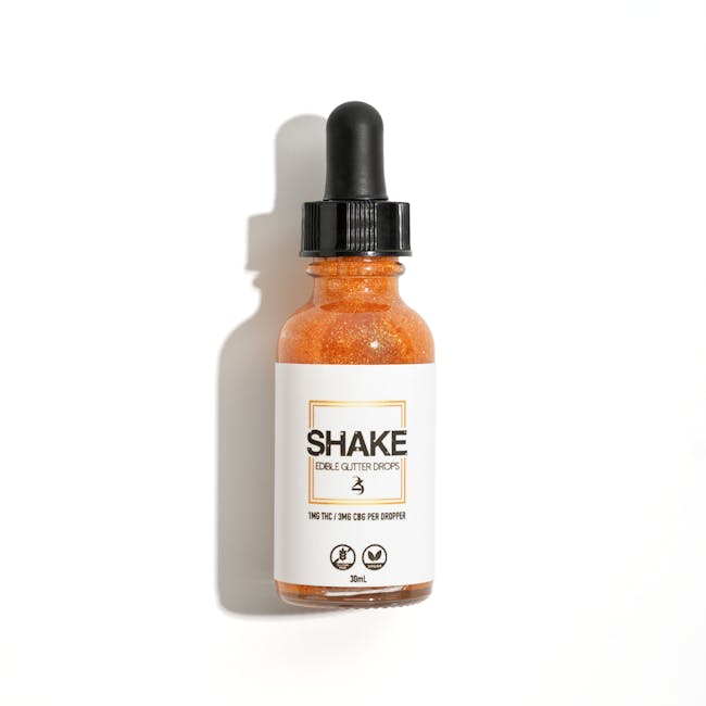 A bottle of Shake edible glitter drops with a dropper, isolated on a white background.