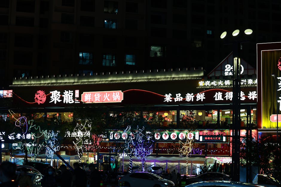 Illuminated Asian street market at night with colorful lights and signage.