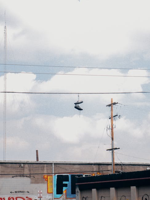 Street view of sneakers hanging on power lines against cloudy sky in Denver.