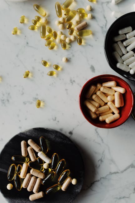 A flat lay of various pills and capsules on a marble surface, emphasizing health and medicine.