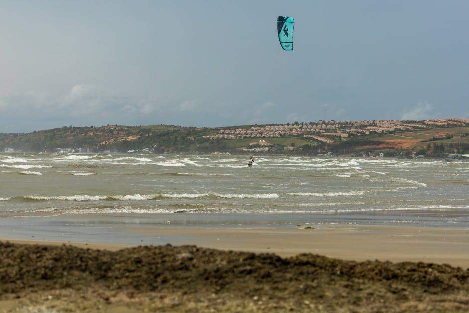 Exciting kitesurfing at a sandy beach with rolling waves and clear skies.