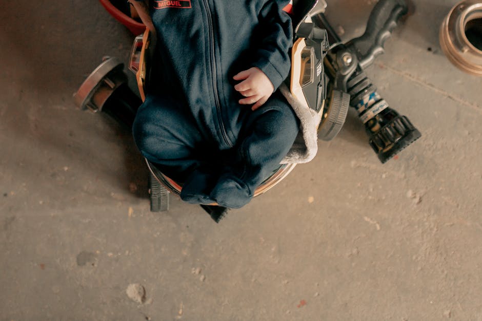 Cute baby sitting on mechanical equipment wearing a blue outfit, showcasing a unique perspective.