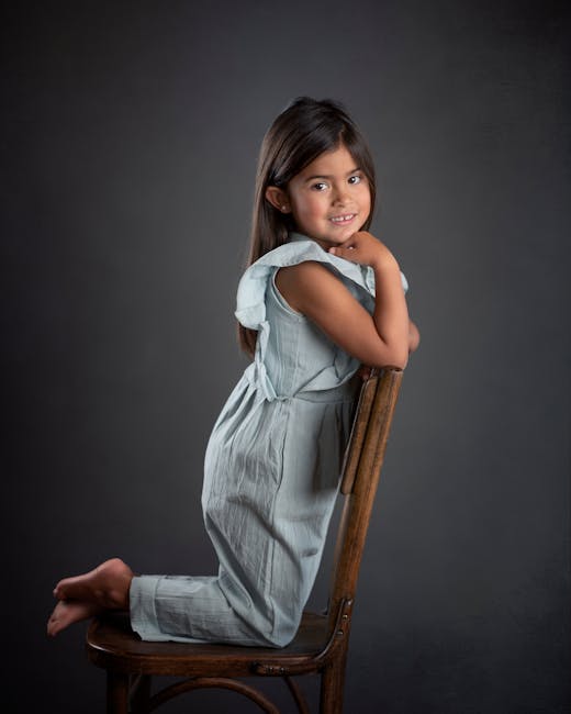 Delightful studio portrait of a young girl posing on a chair, full of warmth and charm.