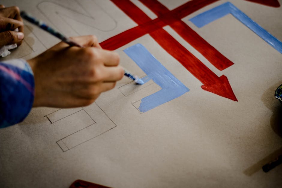 Artistic close-up of a hand painting colorful arrows on paper, showcasing creativity and craftsmanship.