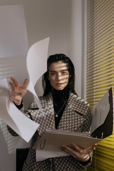 A businesswoman in a coat tosses papers in an office setting, conveying a dynamic workplace scene.