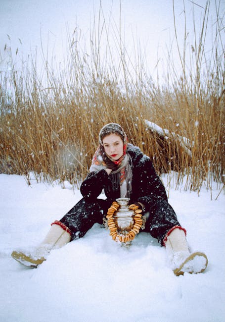 Woman in winter clothes with bagels and samovar, seated in snowy Russian field.