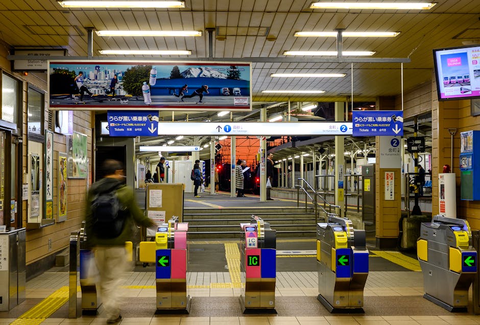 A busy evening scene at a Japanese train station featuring ticket gates and passengers entering the platform area.