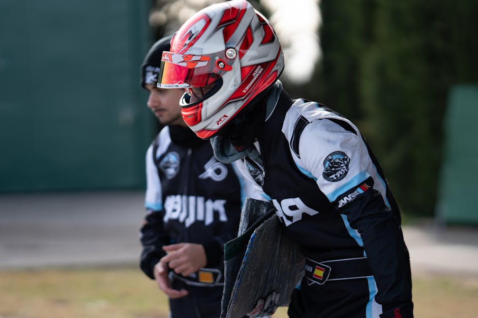 Two go-kart racers in helmets and racing gear prepare for an outdoor race, exuding focus and determination.
