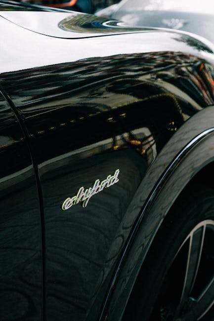 Close-up view of a shiny black hybrid car focusing on the emblem and fender detailing.