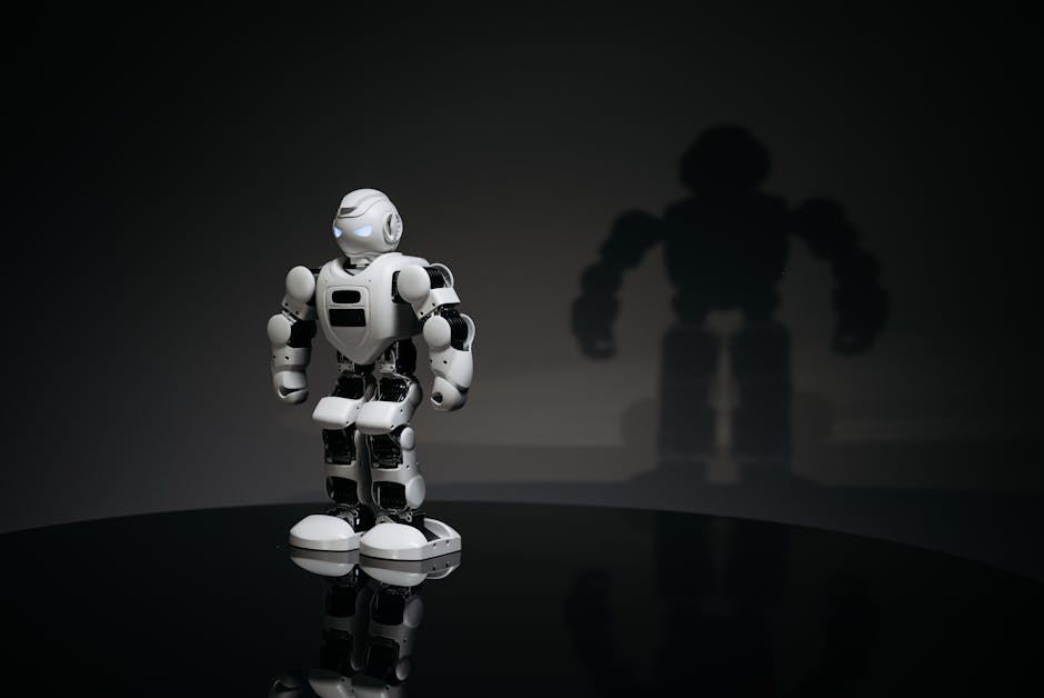 A white and black toy humanoid robot in a studio setting casting a shadow.