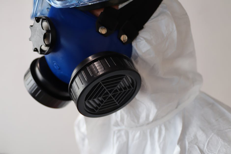 Close-up image of a protective respirator mask and white protective suit, emphasizing safety.