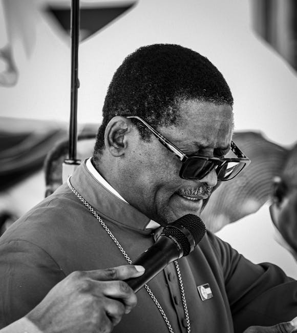Black and white image of a man in sunglasses giving a public speech.