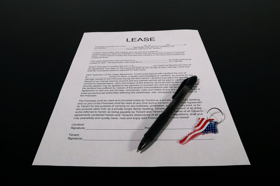 Lease agreement document with pen and American flag keychain on a black table.