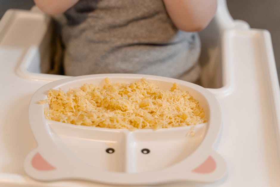 Close-up of a baby in a high chair enjoying scrambled eggs during meal time.