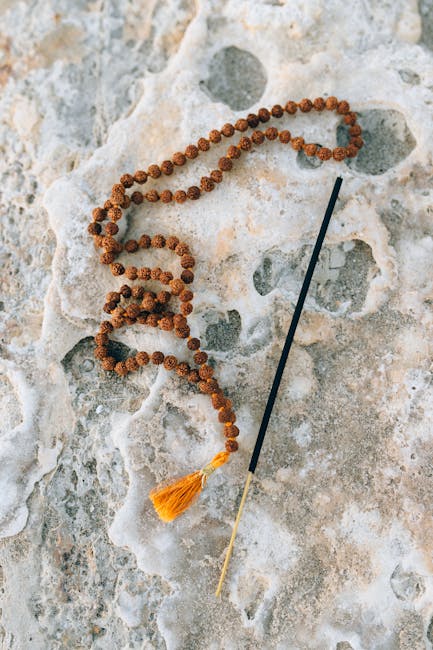 Prayer beads and incense stick on a natural stone surface, evoking meditation and peace.