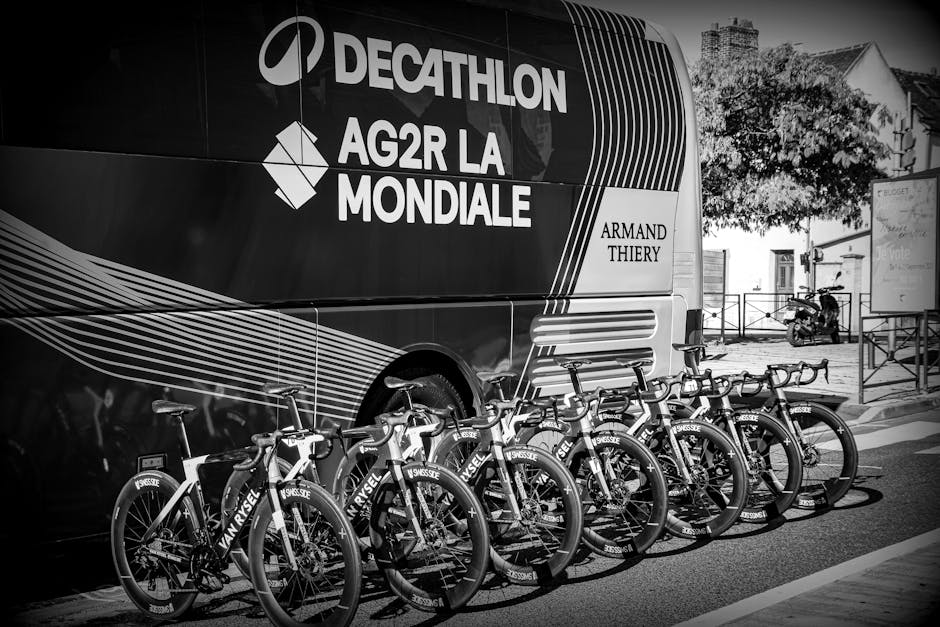 Row of professional racing bicycles lined up in front of team bus, monochrome style.