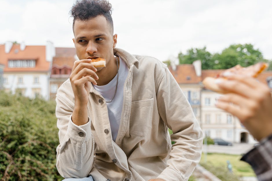A young man casually enjoying a slice of pizza in a European city setting.